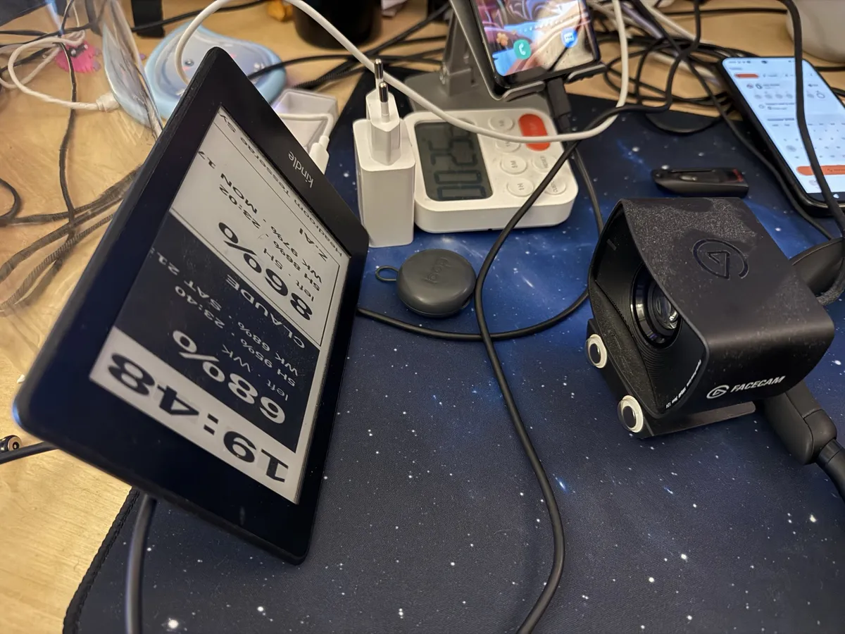 A Kindle on a desk shows a broken dashboard, only its left half, stretched. A webcam on the right points at it.